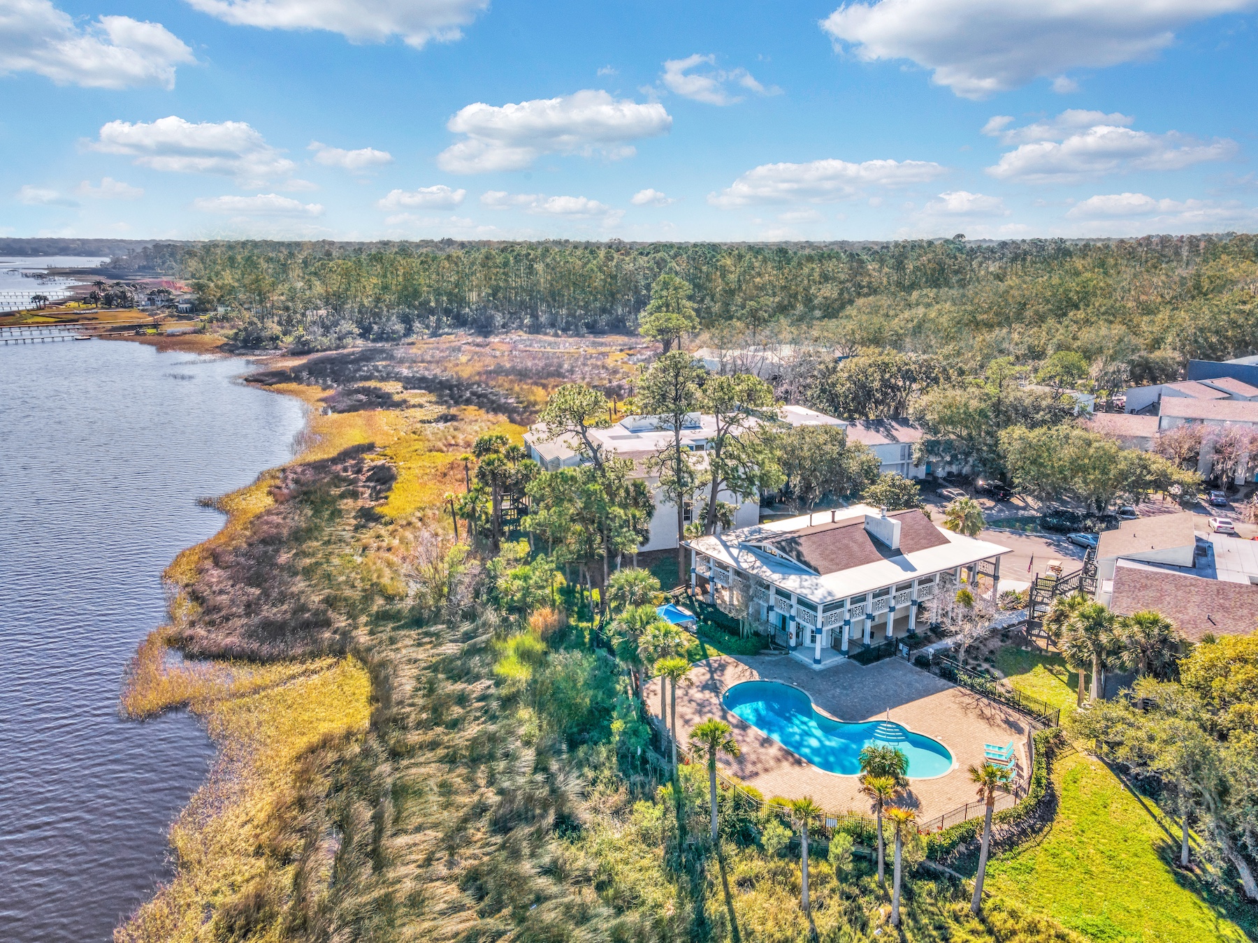 Aerial view of community with a lush grass lawn, lake view, and a pool.